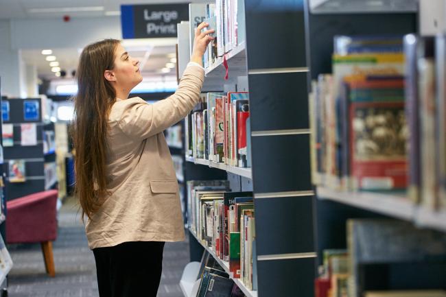Person searching through library shelf